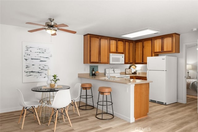 kitchen with white appliances, light hardwood / wood-style flooring, kitchen peninsula, and ceiling fan