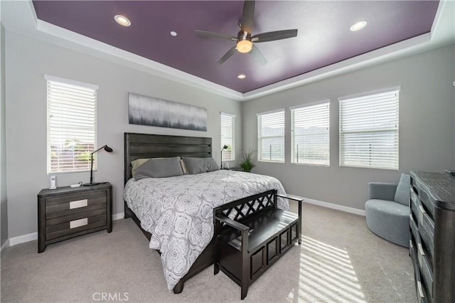 bedroom featuring light carpet, ceiling fan, and a tray ceiling