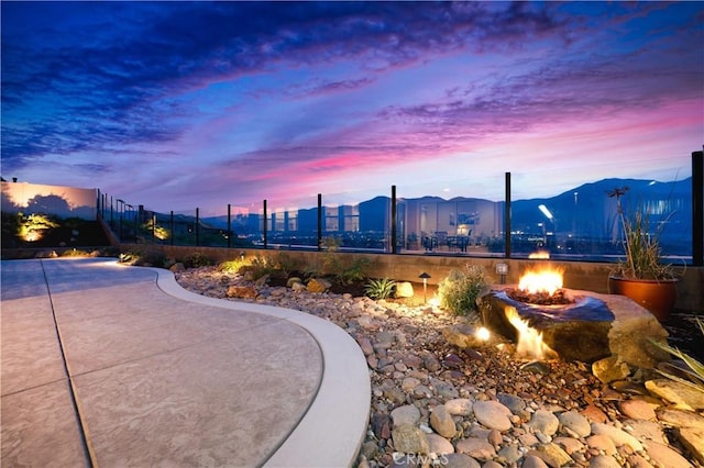 view of property's community featuring an outdoor fire pit, a mountain view, and fence