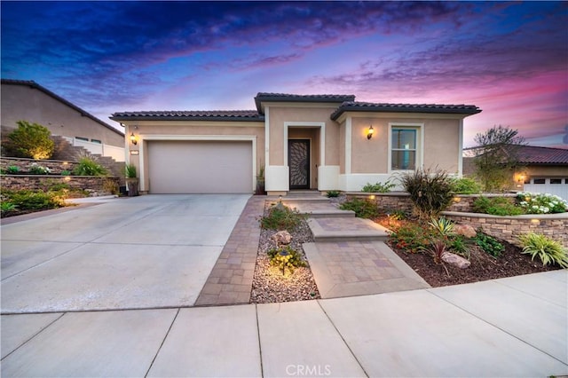 view of front of property with an attached garage, driveway, a tile roof, and stucco siding