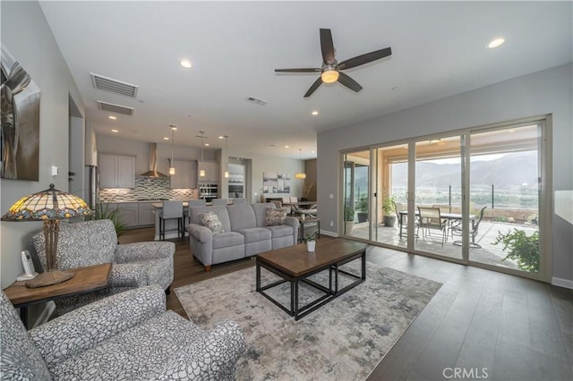 living room with dark wood-type flooring and ceiling fan