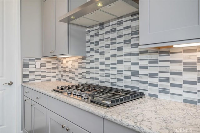 kitchen with tasteful backsplash, gray cabinets, wall chimney exhaust hood, and stainless steel gas stovetop