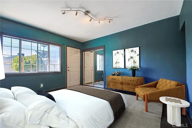 carpeted bedroom with rail lighting and a closet