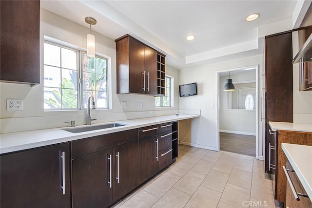 kitchen featuring sink, light tile patterned floors, dark brown cabinets, and hanging light fixtures