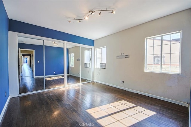 unfurnished bedroom with multiple closets, dark hardwood / wood-style flooring, and multiple windows