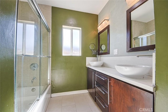 bathroom with tile patterned flooring, vanity, and bath / shower combo with glass door