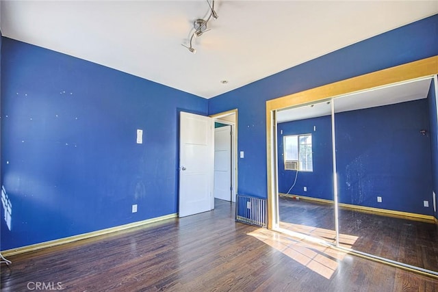 unfurnished bedroom featuring hardwood / wood-style flooring, rail lighting, and a closet