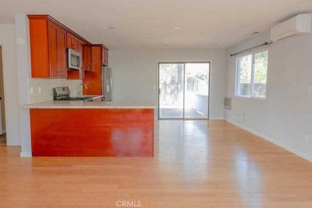 kitchen featuring sink, backsplash, stainless steel appliances, a wall mounted AC, and light wood-type flooring