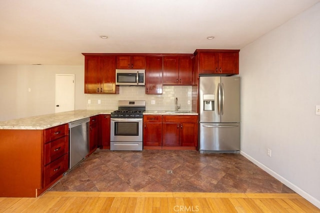 kitchen featuring sink, appliances with stainless steel finishes, dark hardwood / wood-style floors, tasteful backsplash, and kitchen peninsula