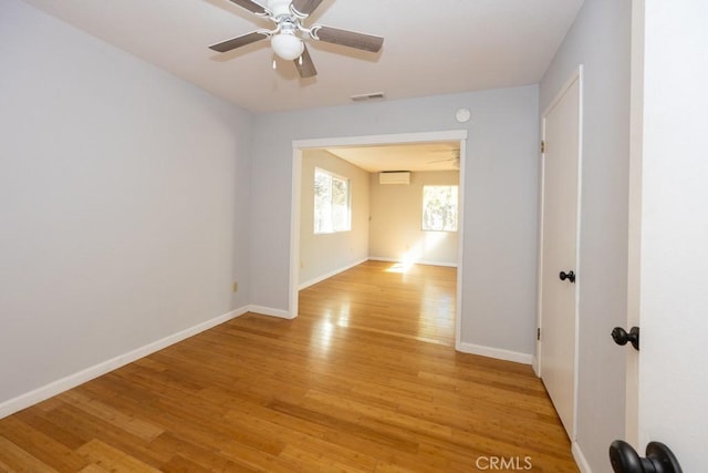 spare room featuring ceiling fan, a wall mounted air conditioner, and light hardwood / wood-style flooring