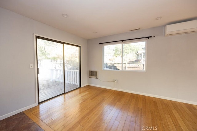 empty room with light hardwood / wood-style flooring and an AC wall unit