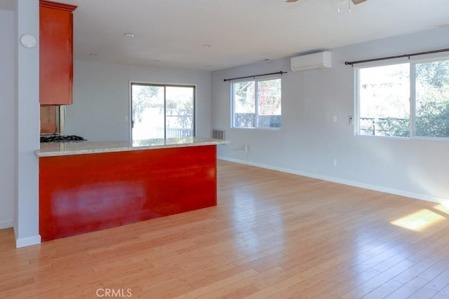 interior space with a wall mounted AC, light hardwood / wood-style floors, and kitchen peninsula