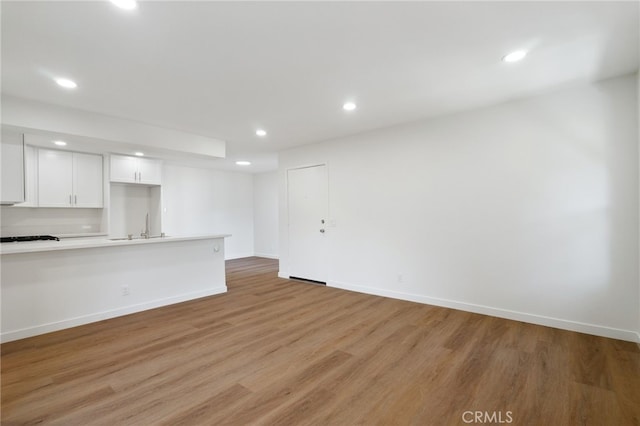 unfurnished living room with light wood-type flooring and sink