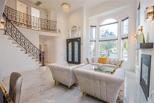 living room featuring a towering ceiling, an inviting chandelier, and french doors