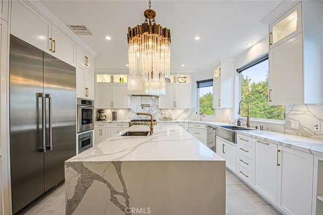 kitchen featuring hanging light fixtures, appliances with stainless steel finishes, sink, and a center island with sink