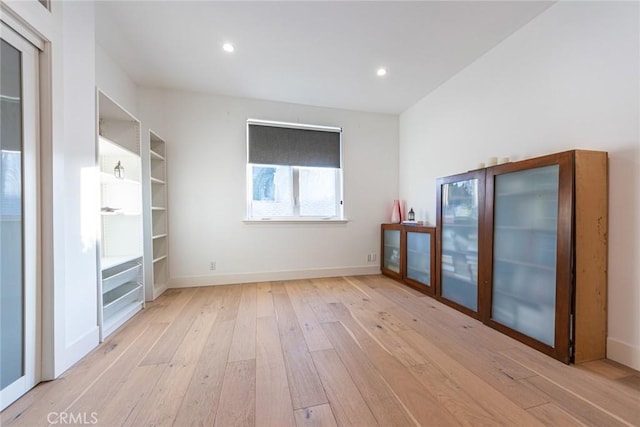 unfurnished room featuring built in shelves and light hardwood / wood-style flooring