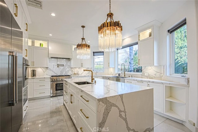 kitchen with white cabinetry, sink, an island with sink, and premium appliances