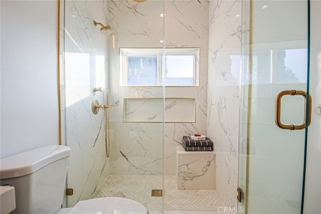 bathroom featuring a shower with shower door and toilet