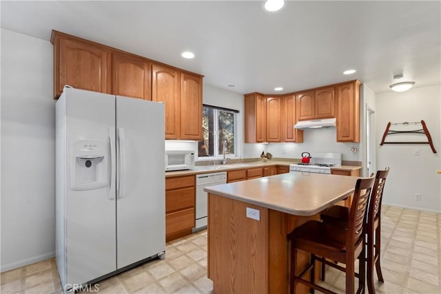 kitchen featuring a center island, light floors, light countertops, white appliances, and under cabinet range hood