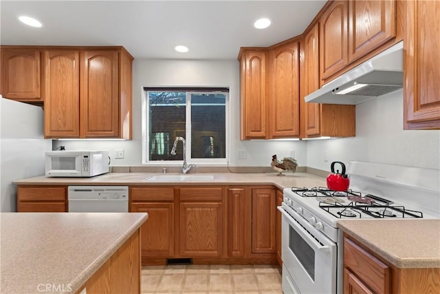 kitchen featuring light countertops, white appliances, a sink, and under cabinet range hood