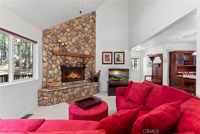 living area with high vaulted ceiling, a stone fireplace, carpet flooring, and visible vents