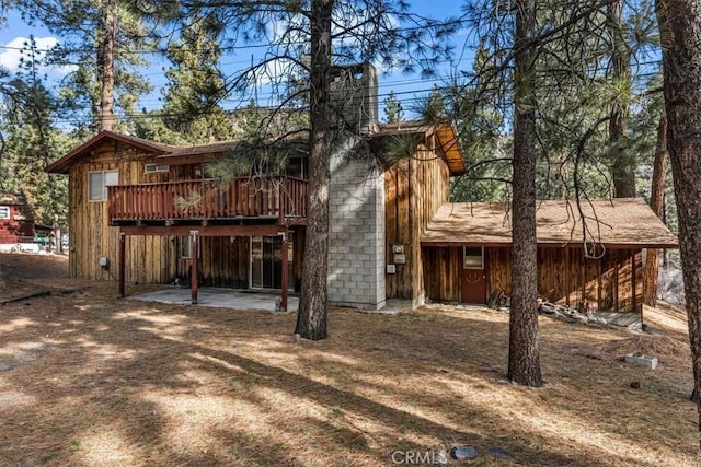 rear view of house with a wooden deck and a patio area