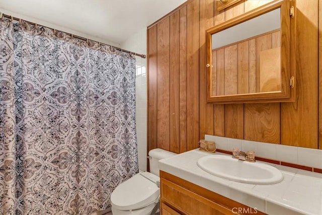 bathroom with a shower with curtain, vanity, toilet, and wood walls