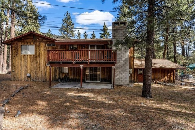 rear view of property with a wooden deck and a patio area