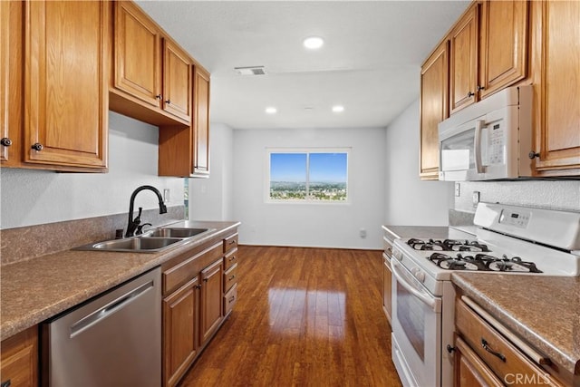 kitchen featuring white appliances, dark wood-style flooring, a sink, and brown cabinetry