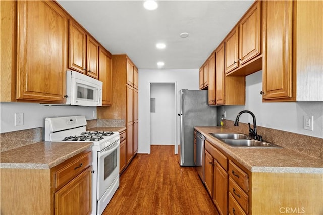 kitchen with recessed lighting, stainless steel appliances, wood finished floors, a sink, and brown cabinetry