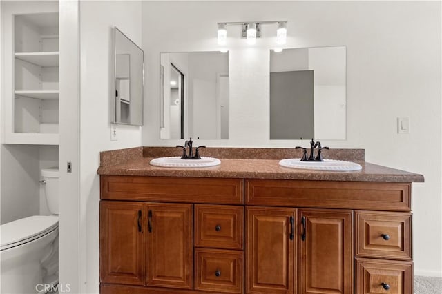 bathroom featuring toilet, double vanity, and a sink