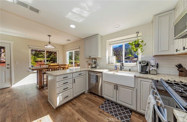 36763 Venado Dr, Coarsegold, CA 93614 - kitchen featuring stainless steel appliances, a peninsula, dark wood-style flooring, decorative backsplash, and light stone countertops