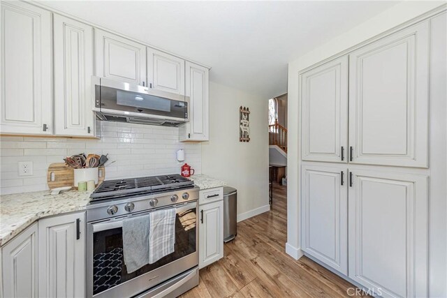 36763 Venado Dr, Coarsegold, CA 93614 - kitchen with stainless steel appliances, light wood-style flooring, tasteful backsplash, and white cabinets