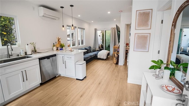 kitchen featuring white cabinetry, sink, a wall mounted AC, hanging light fixtures, and stainless steel dishwasher