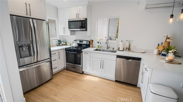 kitchen featuring sink, white cabinets, hanging light fixtures, light hardwood / wood-style floors, and stainless steel appliances