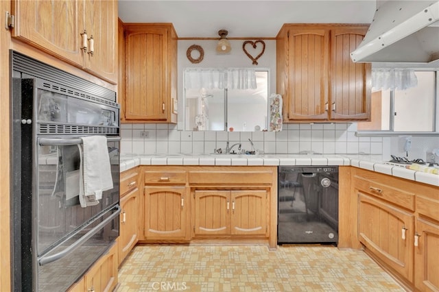 kitchen with light floors, backsplash, a sink, under cabinet range hood, and black appliances