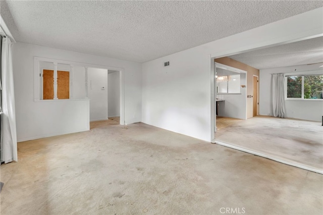 unfurnished room with carpet floors, visible vents, and a textured ceiling