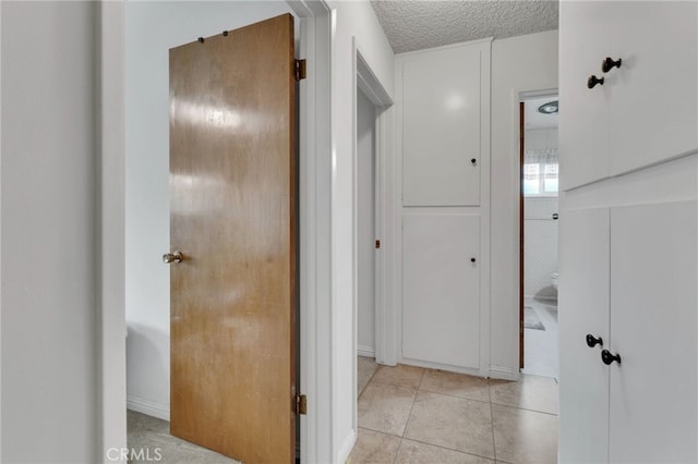 hall with a textured ceiling and light tile patterned flooring