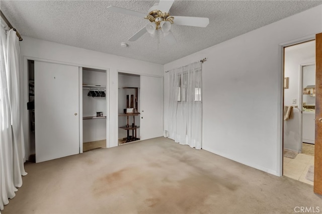 unfurnished bedroom featuring multiple closets, carpet, ceiling fan, and a textured ceiling