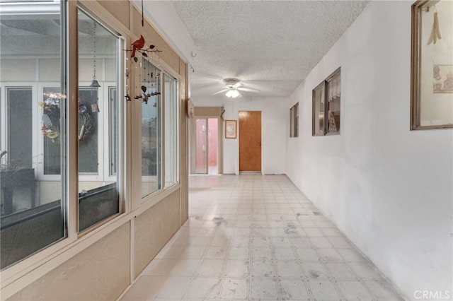 hall with a textured ceiling and light floors