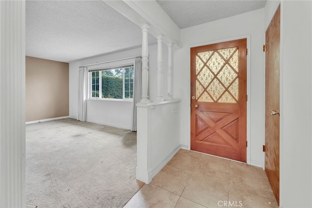 doorway featuring baseboards, a textured ceiling, and light colored carpet