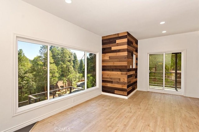 spare room featuring wood walls and light wood-type flooring