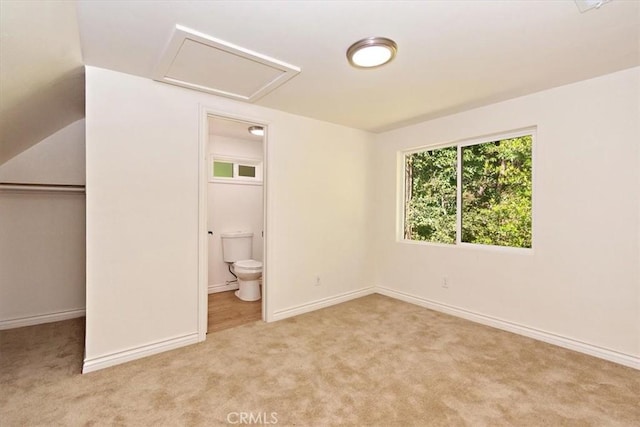 unfurnished bedroom featuring ensuite bath, light colored carpet, and a closet