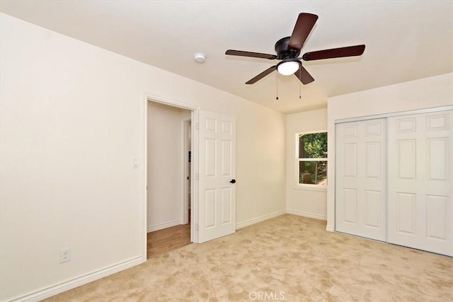 unfurnished bedroom with light carpet, ceiling fan, and a closet