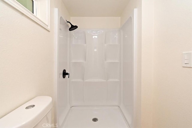 bathroom featuring a shower and toilet