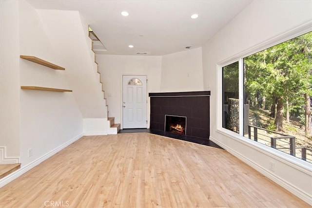 unfurnished living room with plenty of natural light, light hardwood / wood-style floors, and a tile fireplace