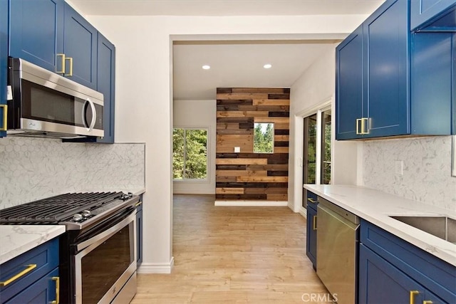 kitchen with plenty of natural light, stainless steel appliances, light hardwood / wood-style floors, and blue cabinetry