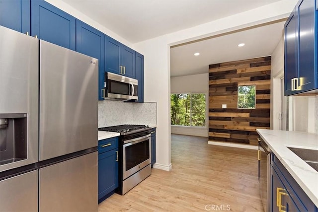 kitchen with appliances with stainless steel finishes, wooden walls, blue cabinets, and decorative backsplash