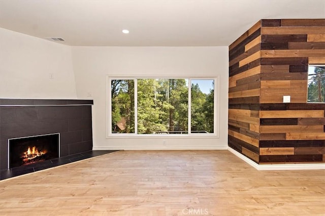 unfurnished living room with a tile fireplace and light hardwood / wood-style flooring