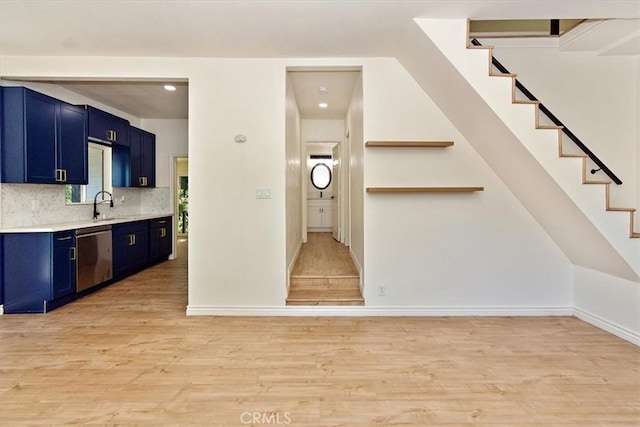 interior space featuring blue cabinetry, sink, tasteful backsplash, light wood-type flooring, and dishwasher